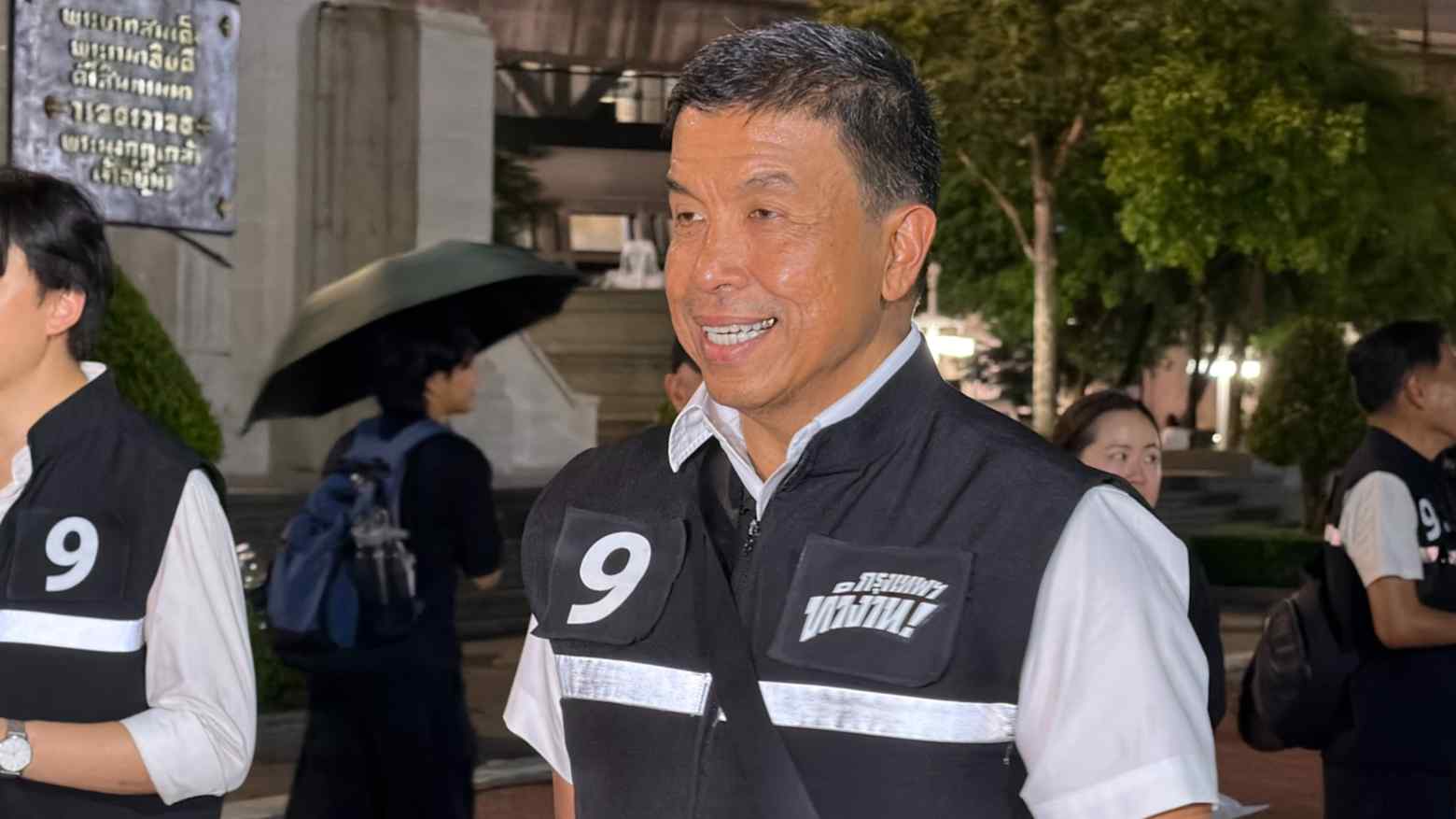 Chadchart Sittipunt smiling in a number nine campaign vest outside Bangkok City Hall