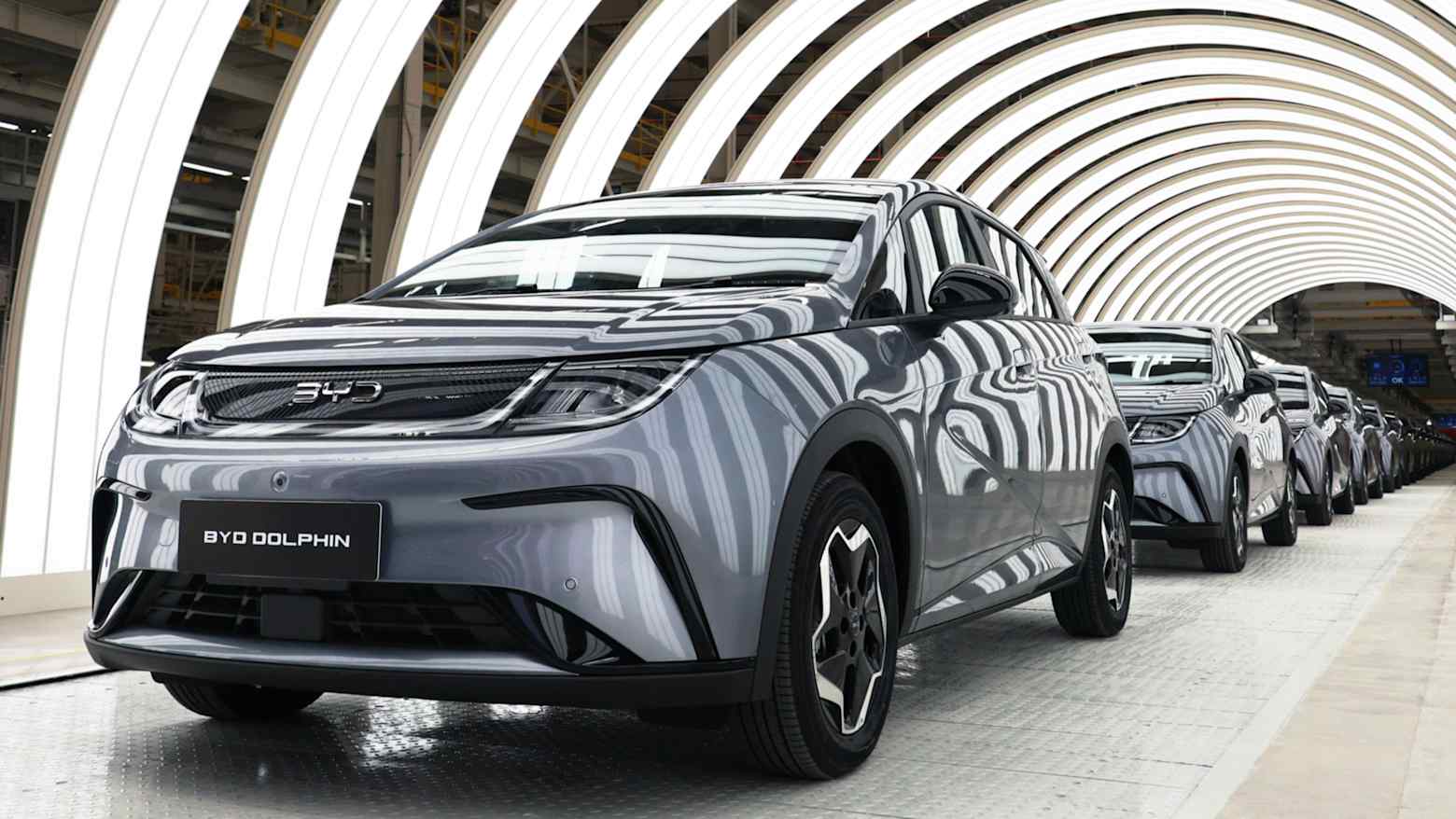 A row of grey BYD Dolphin electric cars lined up along a factory production line