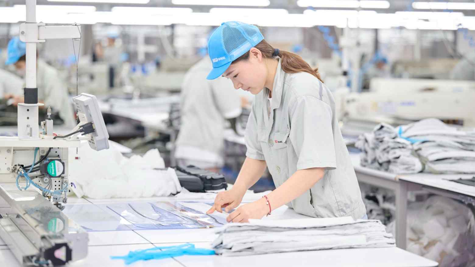 A worker inspects garments on a production line at a Fast Retailing supplier factory