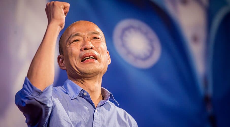 Han Kuo-yu raising his fist at a rally in front of a Taiwan flag