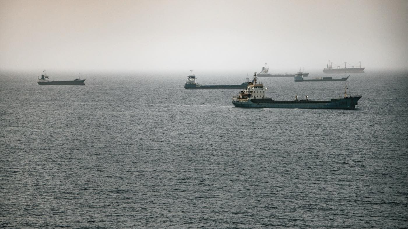 Cargo ships waiting in the Strait of Hormuz under a hazy sky