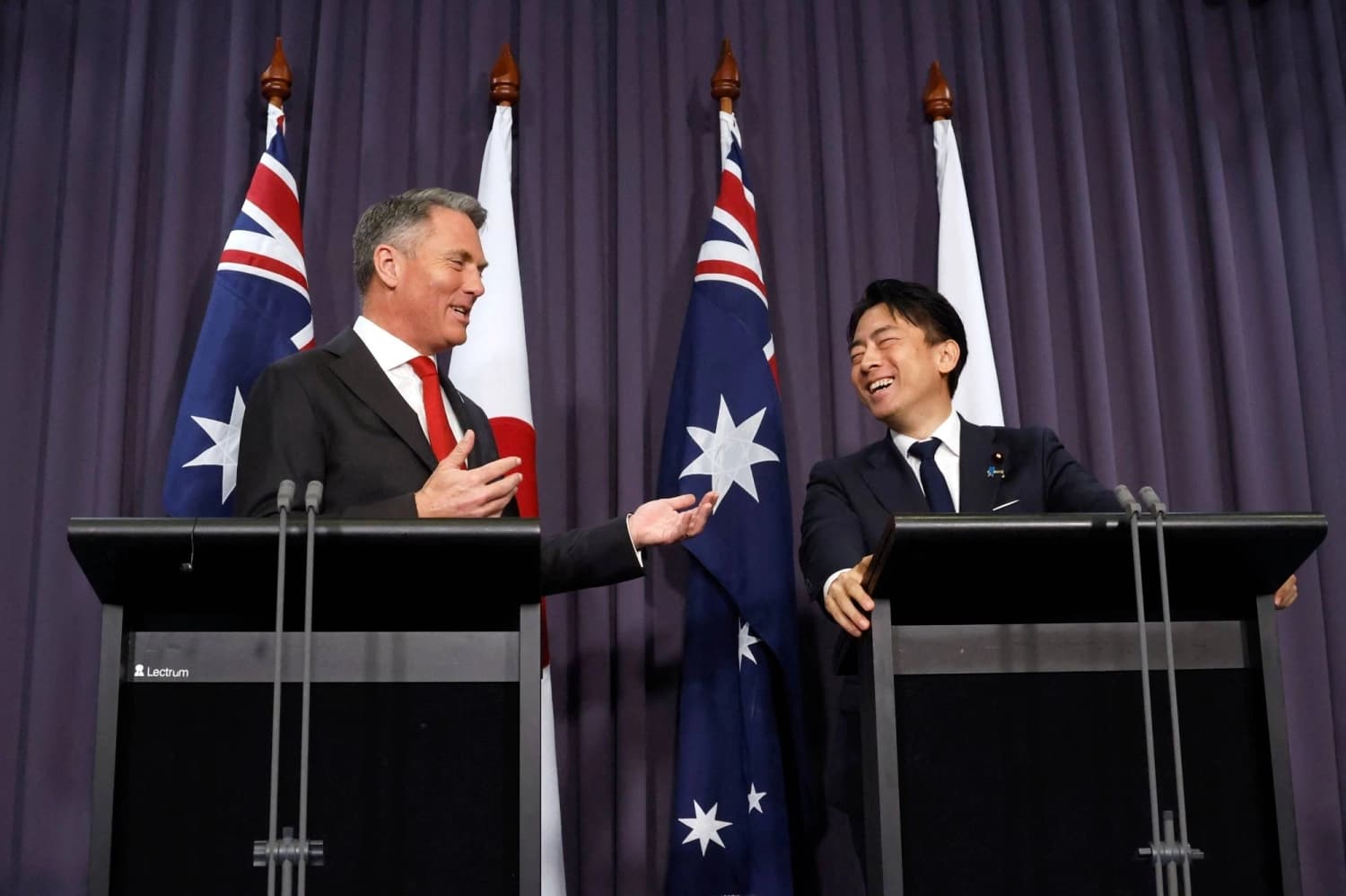 Australian Deputy Prime Minister Richard Marles and Japanese Defense Minister Shinjiro Koizumi share a light moment at a joint press conference in front of Australian and Japanese flags