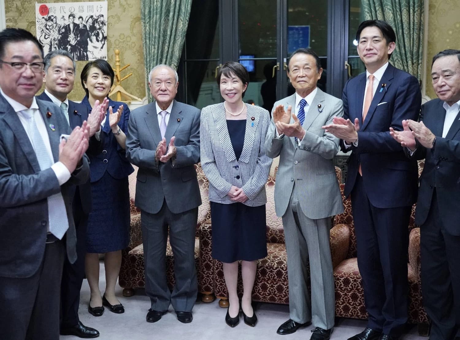 Japanese Prime Minister Sanae Takaichi with senior LDP lawmakers applauding at a party gathering