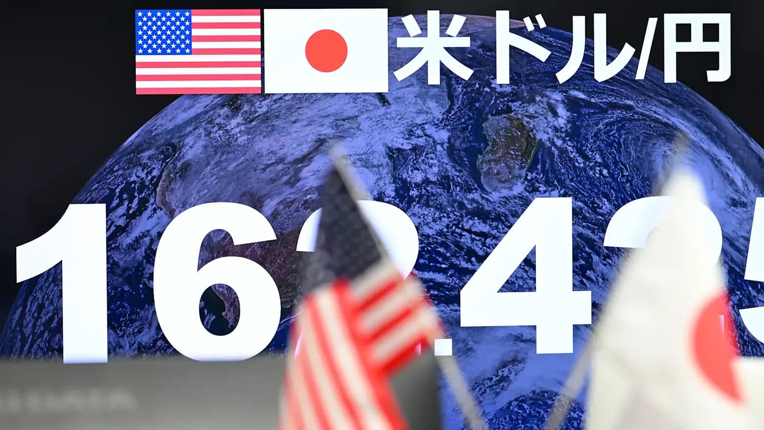 An electronic board in Tokyo showing the US dollar to yen exchange rate alongside American and Japanese flags