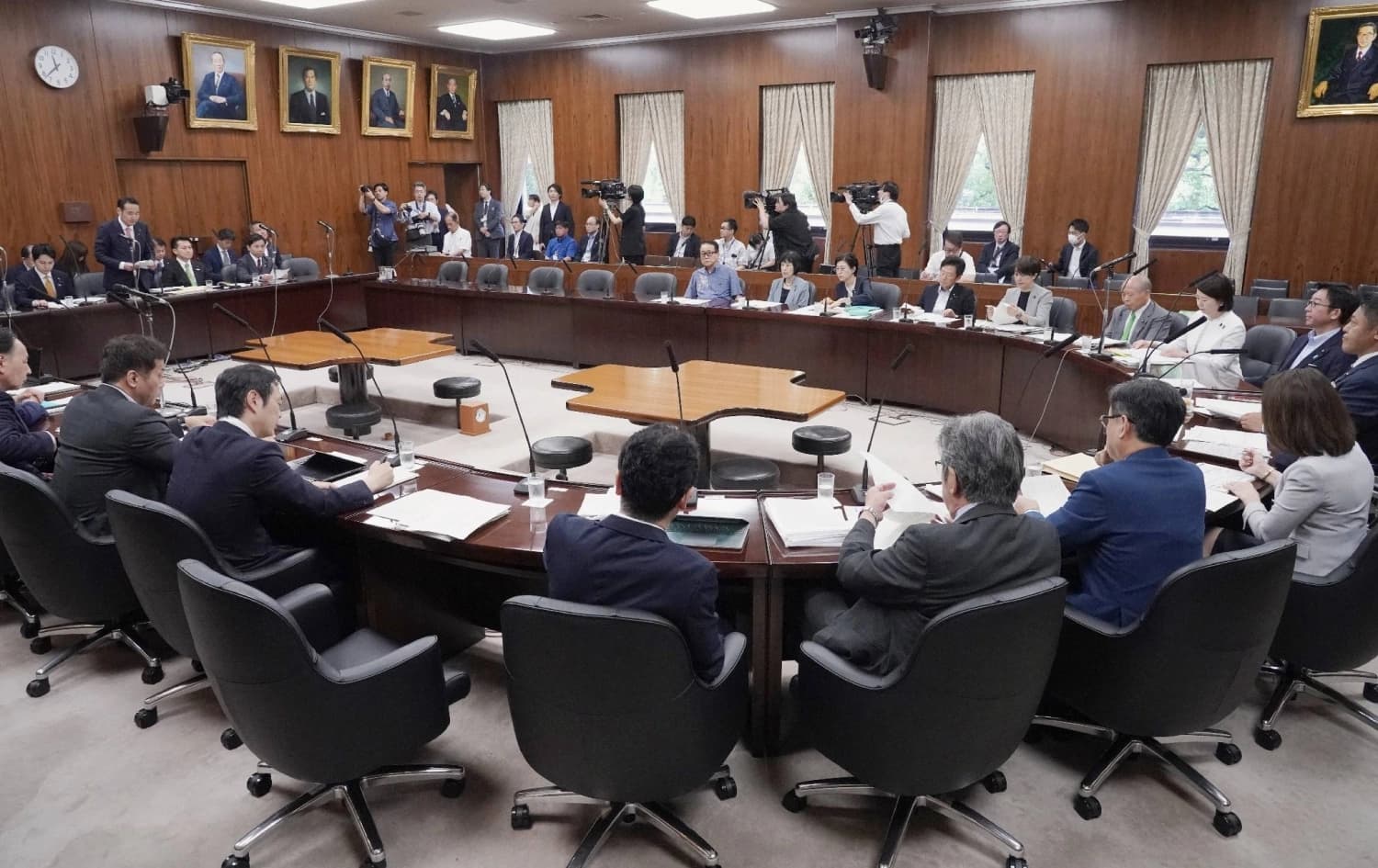 Members of a Diet committee seated around a horseshoe table during a parliamentary session in Tokyo