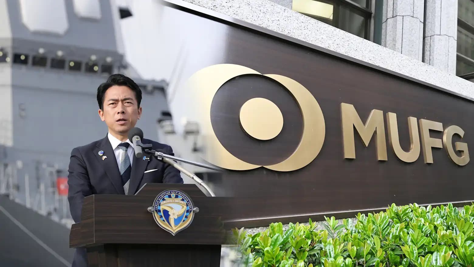 A Japanese official speaking at a podium beside a naval vessel, next to an MUFG signage board