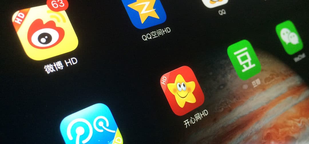 A tablet screen displaying Chinese social media apps including Weibo, QQ and WeChat