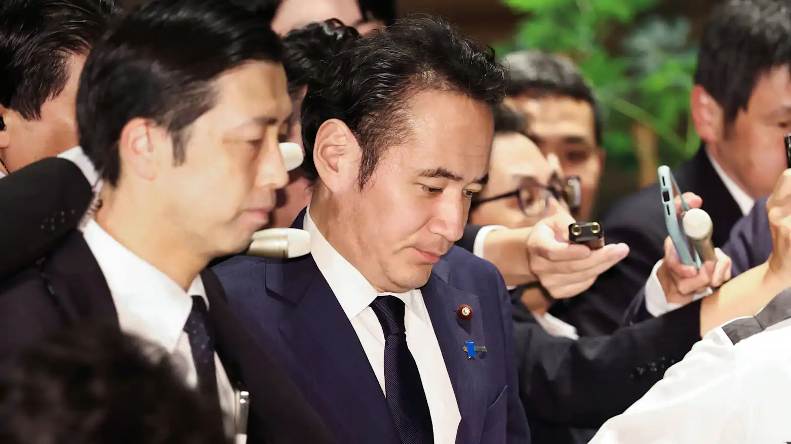 Japan's agriculture minister Kazuo Yana surrounded by reporters and microphones after a press scrum