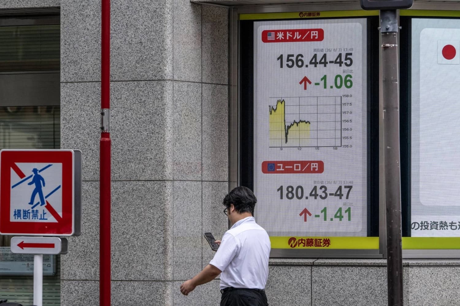 A man walks past an electronic board displaying the dollar-yen exchange rate in Tokyo